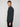A young man with short light brown hair stands sideways, wearing the PROJEK RAW MENS LONG SLEEVE 4WAY STRETCH TWILL SHIRT and black pants against a plain light gray background, looking at the camera.